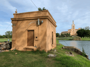 The historic Gondola Building sits beside a waterway in Coral Gables with the Biltmore Hotel visible in the background.