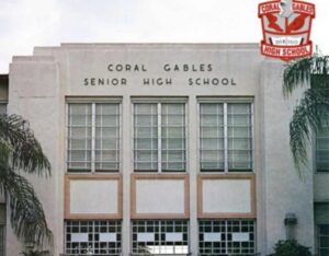 Undated photo of the front facade of Coral Gables Senior High School, showing art deco architecture with tall windows, palm trees, and the school crest in the corner.