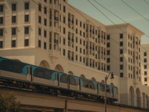 A Metrorail train passes through Coral Gables near new mixed-use buildings along U.S. 1, illustrating how population growth is intensifying the need for an integrated city-and-regional mobility strategy.