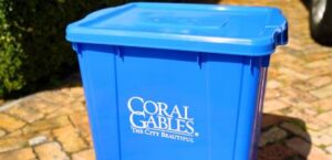 Blue Coral Gables recycling bin on a brick driveway, symbolizing local garbage and sanitation services.