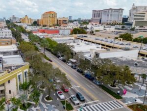 Aerial photo of Miracle Mile in downtown Coral Gables showing tree-lined streets, parked cars, and surrounding commercial buildings as the city considers plans to attract more visitors and strengthen the retail corridor.