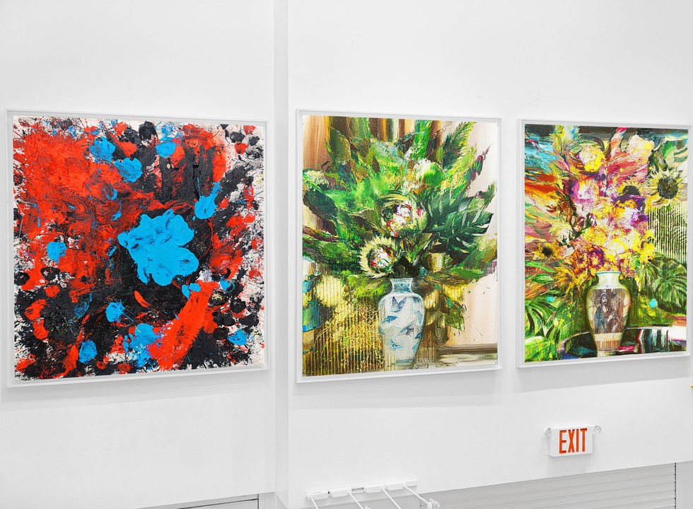 Three large contemporary paintings hang side by side on a white gallery wall at Cernuda Arte in Coral Gables, including an abstract red-and-blue composition and two vivid floral still lifes.