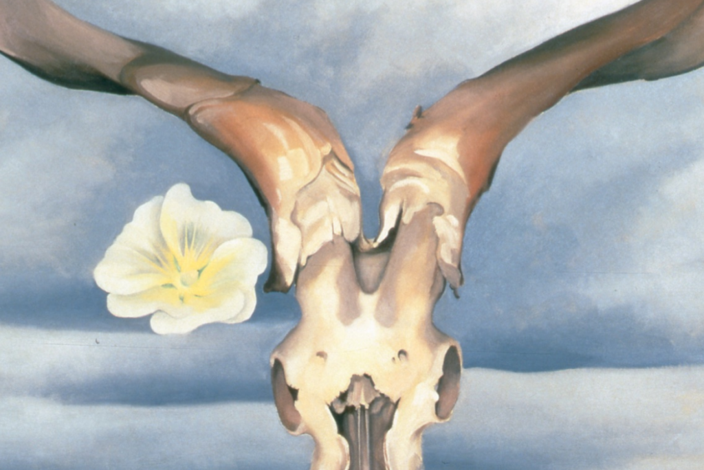 Painting by Georgia O’Keeffe showing a stylized animal skull held by hands with a pale flower against a blue sky background.
