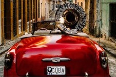 Poster image showing a red vintage car on a Havana street with a tuba mounted on the back.