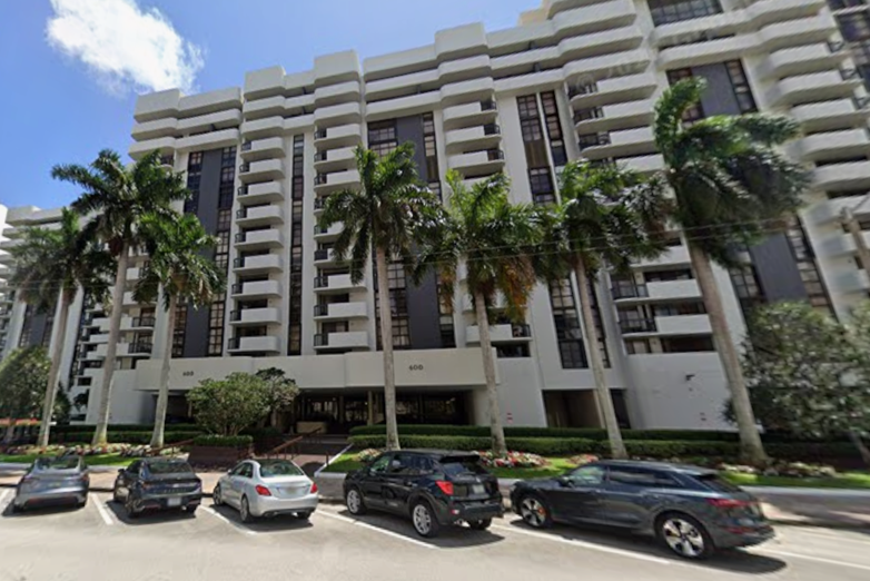 Exterior of the Biltmore II Condominium at 600 Biltmore Way in Coral Gables, with palm trees and parked cars in front.