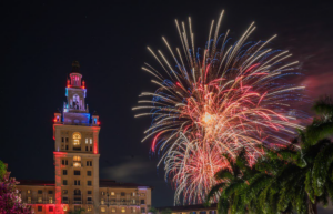 Fireworks burst in the night sky beside the illuminated tower of the Biltmore Hotel in Coral Gables.