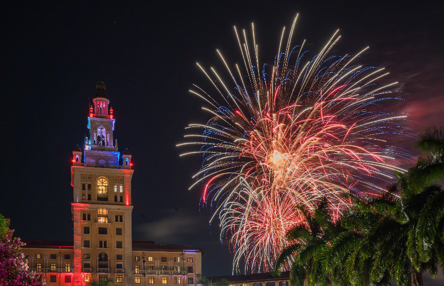 Fireworks burst in the night sky beside the illuminated tower of the Biltmore Hotel in Coral Gables.