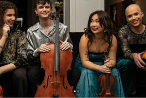 Four members of Poiesis Quartet sit together with string instruments, including a cello, violin and viola.