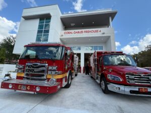 Coral Gables Firehouse 4 with two red fire rescue vehicles parked outside the station bays under a blue sky.