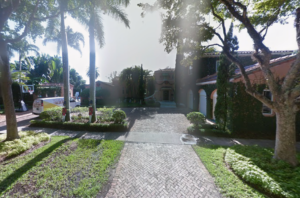 Street-view image of a large Coral Gables home at 4107 Santa Maria St. with a brick driveway, palm trees, landscaping and mature trees near the street.