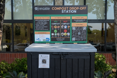 Black compost drop-off bin beneath an instructional sign outside the Coral Gables Library.