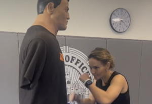 A woman practices a defensive strike against a training mannequin inside a Coral Gables Police Department training room.