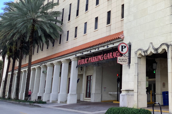Exterior of Coral Gables public parking Garage 2, with palm trees, columns and the garage entrance along Aragon Avenue.