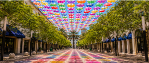 Rows of brightly colored floral-patterned umbrellas suspended above the tree-lined pedestrian walkway at Giralda Plaza in Coral Gables.