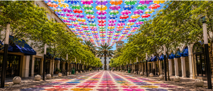 Rows of brightly colored floral-patterned umbrellas suspended above the tree-lined pedestrian walkway at Giralda Plaza in Coral Gables.