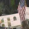 Biltmore Way streetscape contract approved 25% above city estimate Vice Mayor Rhonda Anderson and Mayor Vince Lago hold large presentation boards showing tree species and corridor plans during a Coral Gables City Commission meeting.