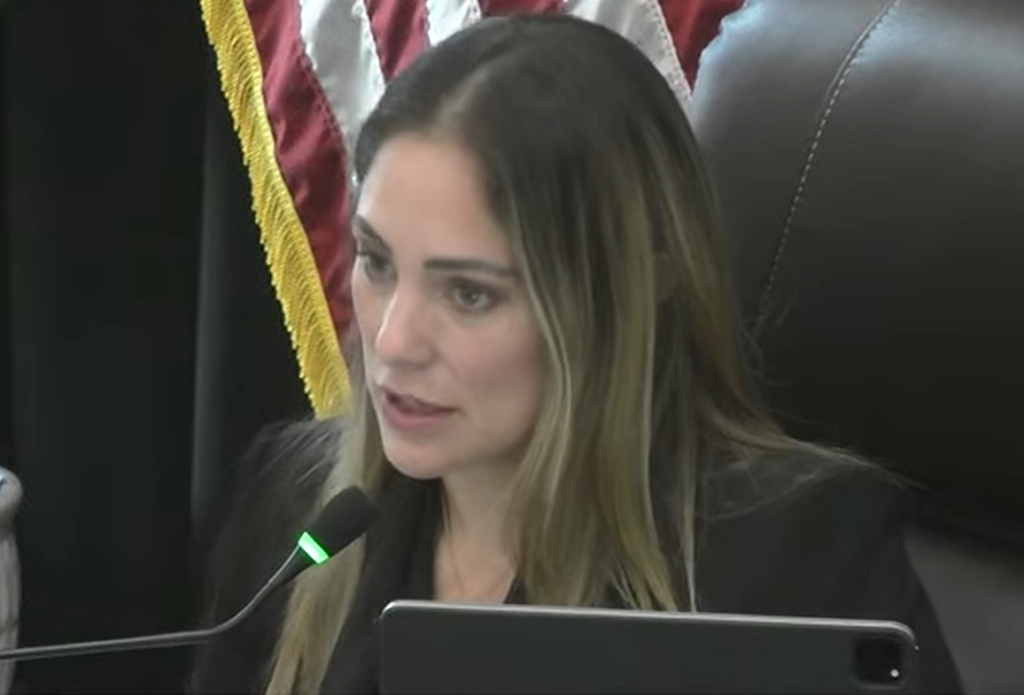 Coral Gables Commissioner Melissa Castro speaks into a microphone from the dais during a City Commission meeting.