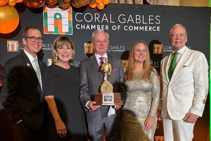From left, Jorge Martinez, Gloria V. Baez, Armando Codina holding the George E. Merrick Award, Maria Garcia and W. Allen Morris pose in front of a Coral Gables Chamber of Commerce backdrop.