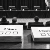 Vote no on the four-year mayoral term. Keep your say over City Hall. Black-and-white editorial illustration of the Coral Gables commission chamber with two sample ballots in the foreground: one labeled “2 Years” with three boxes and one labeled “4 Years” with two boxes.