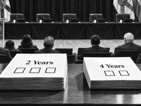 Black-and-white editorial illustration of the Coral Gables commission chamber with two sample ballots in the foreground: one labeled “2 Years” with three boxes and one labeled “4 Years” with two boxes.