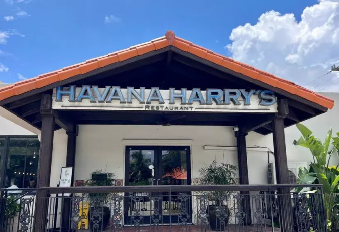 Exterior of Havana Harry’s restaurant in Coral Gables, with its large sign above the entrance under a red-tile roof.