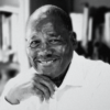 Black-and-white portrait of historian Marvin Dunn smiling with his hand resting beneath his chin.