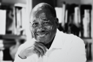 Black-and-white portrait of historian Marvin Dunn smiling with his hand resting beneath his chin.
