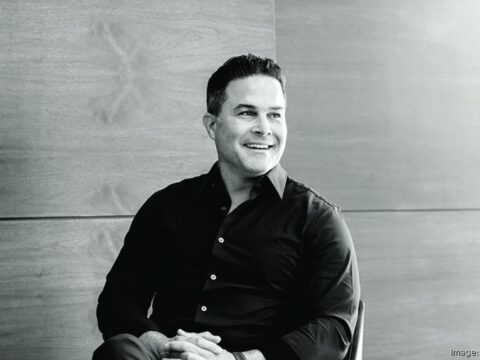 Black-and-white portrait of real estate developer Alberto J. Perez seated indoors and smiling while looking to his left.