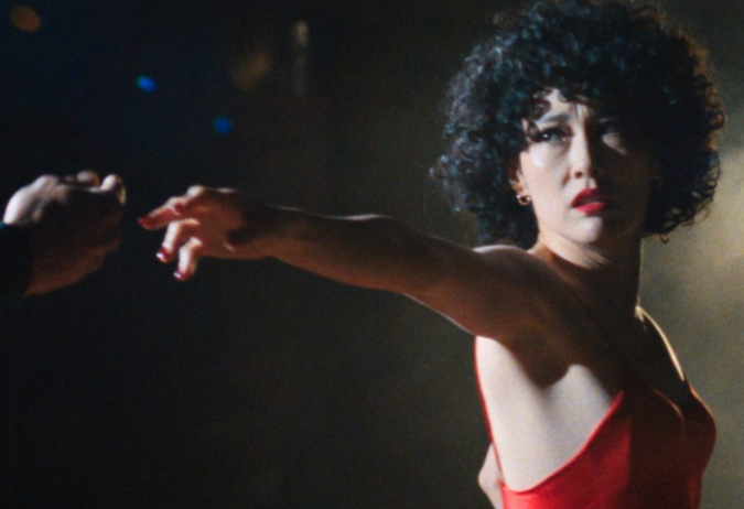 Woman in a red ballroom dress extends her arm toward a dance partner in a dark scene from Ha-Chan, Shake Your Booty!.