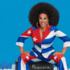 Grammy winner Aymée Nuviola brings ‘90 Millas’ to Sanctuary of the Arts Smiling Cuban vocalist in a red, white and blue suit inspired by the Cuban flag poses against a bright blue background.