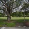 View of the grassy city-owned property at 440 University Drive in Coral Gables, with mature trees, a sidewalk and a streetlight.