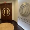 Interior of Cogent Bank’s Coral Gables office, with the bank’s logo mounted on a wall beside wooden double doors and a seating area.