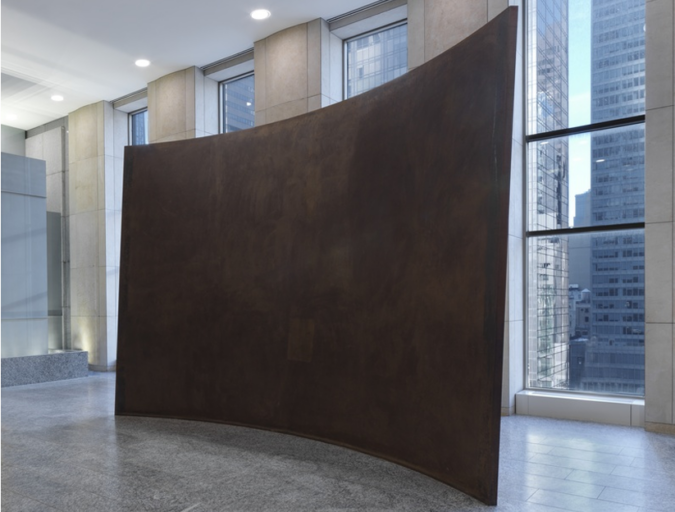Richard Serra's Fin, a large, dark, curved steel wall with a sloping upper edge, displayed in a stone-floored Manhattan office lobby with floor-to-ceiling windows.
