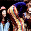 Performers in colorful costumes laugh and pose together onstage during a 1972 Toronto production of “Godspell.”