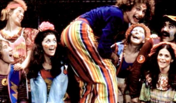 Performers in colorful costumes laugh and pose together onstage during a 1972 Toronto production of “Godspell.”