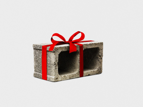 A gray concrete block wrapped like a gift with a bright red ribbon and bow against a white background.