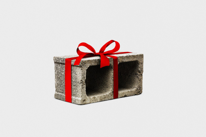 A gray concrete block wrapped like a gift with a bright red ribbon and bow against a white background.