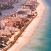 Aerial photograph of Miami Beach showing beachfront hotels, a broad sandy beach, turquoise Atlantic Ocean waters and an inland waterway.