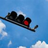 Coral Gables kept $712,000 from red-light cameras, more than triple last year Red traffic signal and mounted red-light enforcement camera against a blue sky with clouds.