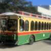 Cream, red and green Coral Gables trolley displaying the Ponce de Leon route against a softly blurred city background.